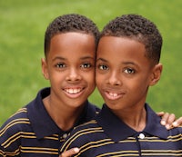 two boys posing for a photo in a grassy field